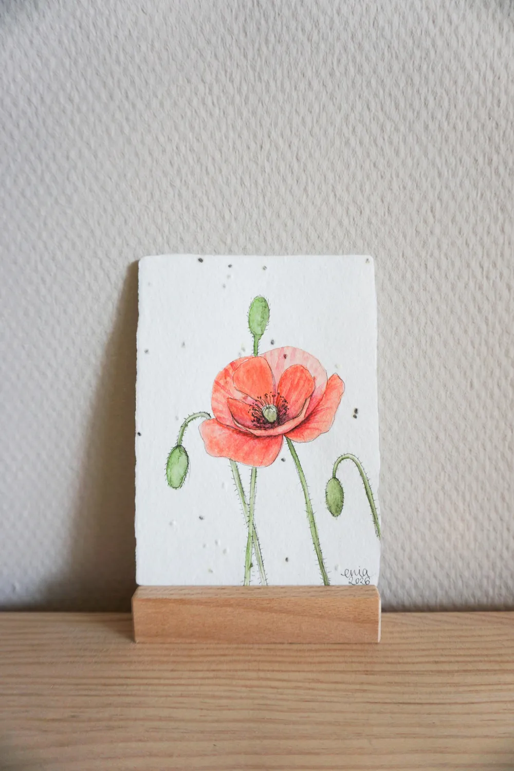 Die zarten Blätter der Mohnblüte bewegen sich sanft im Wind. - auf handgeschöpftem Saatenpapier (Basilikum Samen)