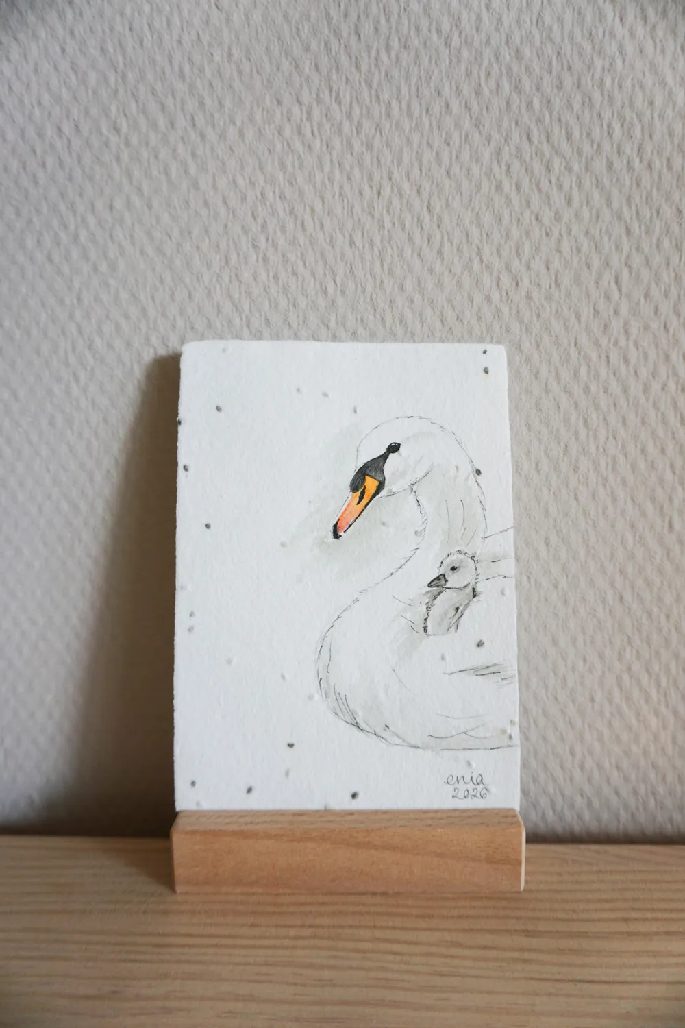 Das Schwanenbaby wird geschützt auf dem Rücken der Mutter getragen. - auf handgeschöpftem Saatenpapier (Basilikum Samen)